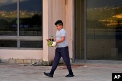 FILE—A boy displaced from his home in southern Lebanon by clashes on the border with Israel carries food distributed to displaced families at a hotel being used as a shelter in the southern town of Marwanieh, Lebanon, March 15, 2024.