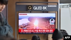 People watch a television showing a news broadcast with file footage of a North Korean missile test, at a railway station in Seoul on January 6, 2025.