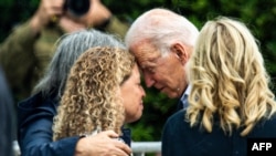 President Joe Biden, with first lady Jill Biden at right, consoles Miami-Dade County Mayor Daniella Levine Cava as he visits a memorial photo wall, near the partially collapsed Champlain Towers South condo building in Surfside, Fla., July 1, 2021. 