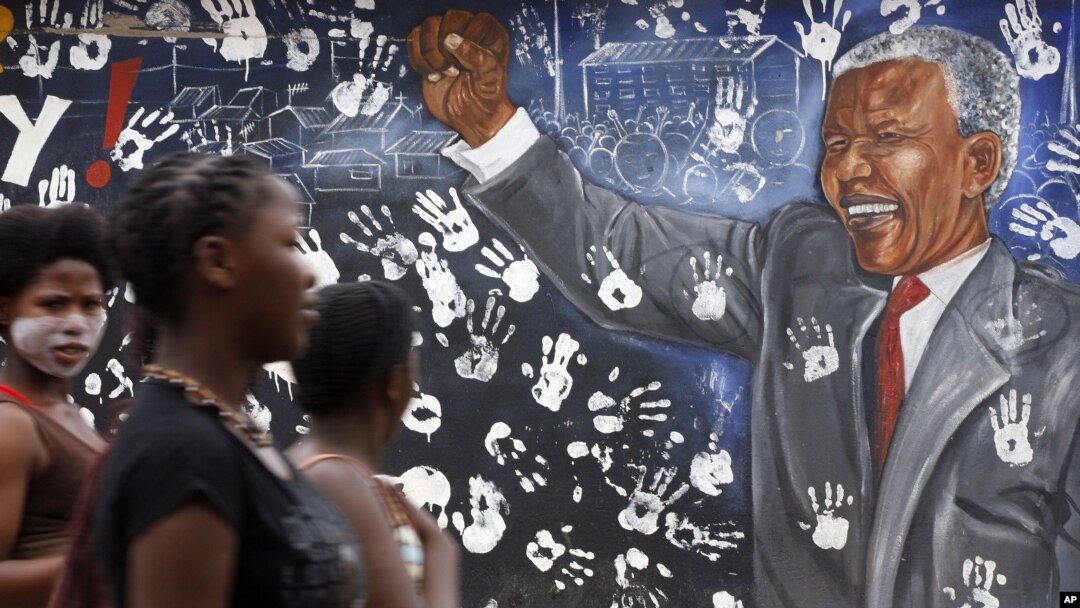 Warga Johannesburg melewati mural yang menggambarkan mantan Presiden Afrika Selatan Nelson Mandela. (AP/Themba Hadebe)