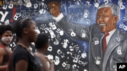 Warga Johannesburg melewati mural yang menggambarkan mantan Presiden Afrika Selatan Nelson Mandela. (AP/Themba Hadebe)