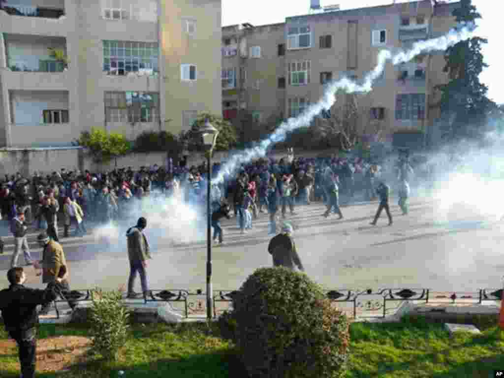 Syrian protesters cover their faces from tear gas being fired in Adlb on December 30, 2011. (Reuters)