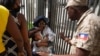 Pripadnik policije Haitija traži od žene da se udalji od ograde Ambasade SAD u Port-Prensu, Haiti, 9. jula 2021.