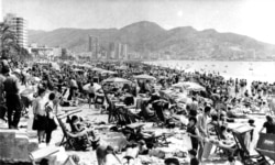 FILE - People enjoy the sunshine and sun bathe on the fashionable Mediterranean beach at Benidorm, Spain in April, 1966.