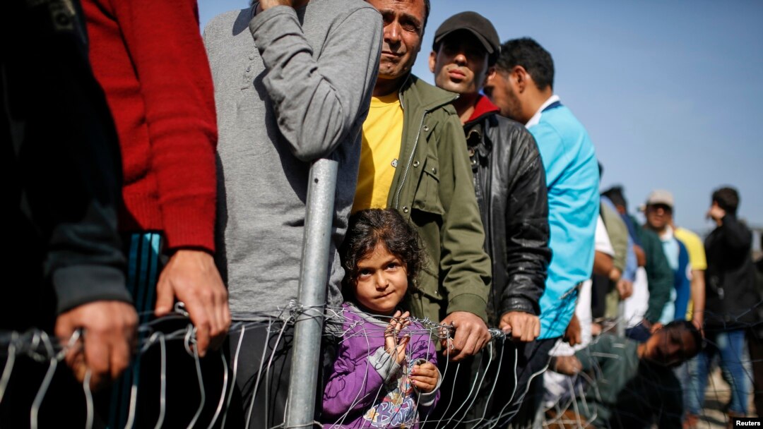 Pengungsi dan migran antri untuk mendapatkan pakaian di tempat penampungan pengungsi di desa Idomeni, perbatasan Yunani-Makedonia (6/4).