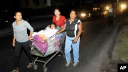 Tiga perempuan mendorong seorang anak yang dalam kereta belanja saat melakukan evakuasi menyusul gempa kuat di Iquique, Chile, Kamis dini hari (3/4). (AP/Cristian Vivero) 