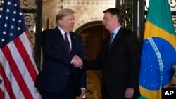 FILE - U.S. President Donald Trump shakes hands with then-Brazilian President Jair Bolsonaro in Palm Beach, Florida, March 7, 2020. Bolsonaro, who is under investigation for several allegations, lost a bid on Jan. 16 to be allowed to leave Brazil to attend Trump's swearing-in.