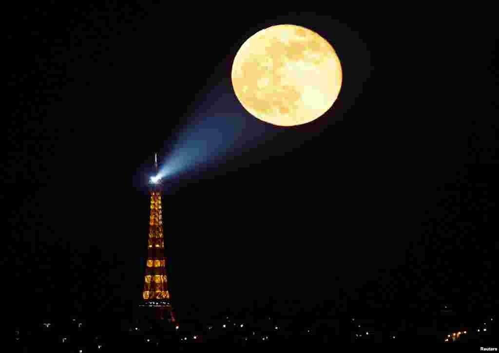The full moon, known as the &quot;Super Pink Moon,&quot; rises behind the Eiffel Tower in Paris, France, April 27, 2021.