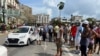 People gather near police cars during protests against and in support of the government, amidst the coronavirus disease (COVID-19) outbreak, outside the Capitol building, in Havana, Cuba, July 11, 2021. 