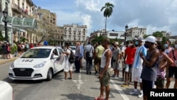 People gather near police cars during protests against and in support of the government, amidst the coronavirus disease (COVID-19) outbreak, outside the Capitol building, in Havana, Cuba, July 11, 2021. 