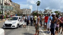 People gather near police cars during protests against and in support of the government, amidst the coronavirus disease (COVID-19) outbreak, outside the Capitol building, in Havana, Cuba, July 11, 2021.