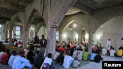 Des croyants écoutent un imam avant de manger à la fin de la journée pendant le Ramadan à Utako, à Abuja, le 16 juillet 2013.