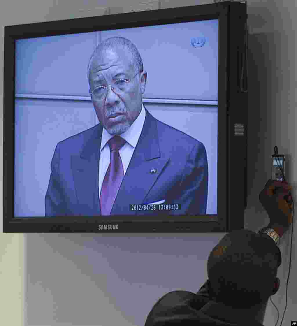 A journalist records the verdict of the judges in the trial against former Liberian President Charles Taylor, seen on the screen standing in the court room of the Special Court for Sierra Leone in Leidschendam, near The Hague, Netherlands. Judges convicte