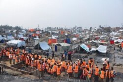 FILE - Volunteers from aid agencies rebuild shelters for Rohingya refugees who lost their dwellings to a fire at Balukhali camp at Ukhiya in Cox's Bazar district, Bangladesh, March 24, 2021.