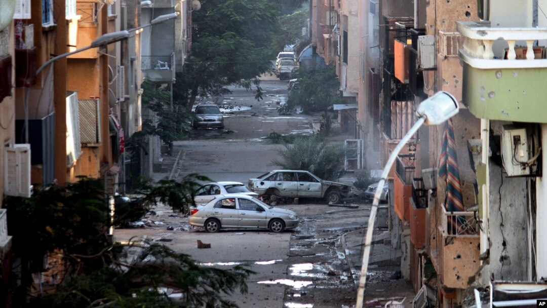 FILE - Damages are seen due to clashes between the Libyan military and Islamic militias in Benghazi, Libya. Representatives of Libya's rival factions who are sitting in Tunis and negotiating through a U.N.-brokered process announced on Tuesday that they have formed a unity government aimed at stemming the chaos that has engulfed the country for the past years.