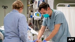 This US Navy handout photo obtained April 6, 2020 shows Lt. Wade Miller, from Orlando, Florida, treating a patient aboard the hospital ship USNS Mercy (T-AH 19)on April 4, 2020 in Los Angeles, California. - Mercy deployed in support of the nation's COVID-