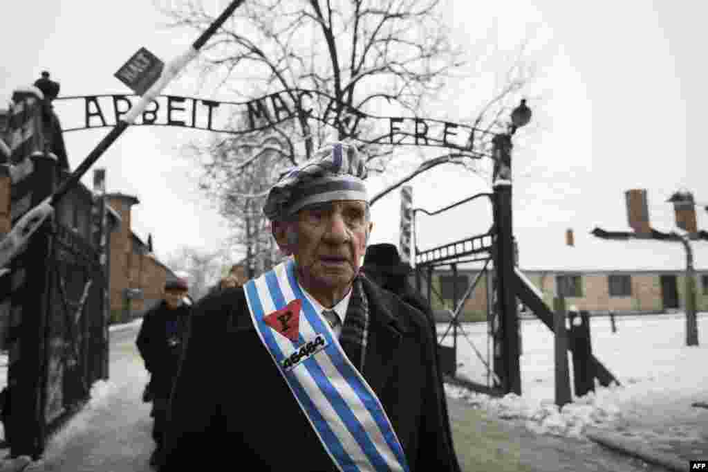 Auschwitz survivor Miroslaw Celka walks out the gate with the sign saying "Work makes you free" after paying tribute to fallen comrades at the "death wall" execution spot in the former Auschwitz concentration camp in Oswiecim, Poland, on the 70th annivers