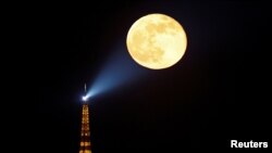The full moon, known as the &quot;Super Pink Moon&quot; rises behind the Eiffel Tower in Paris, France, April 27, 2021.