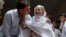 Abdul Aziz Sheikh, left, father of Sabika Sheikh, a victim of a shooting at a Texas high school, comforts an elderly woman at his home in Karachi, Pakistan, May 19, 2018.