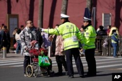 FILE - Chinese police officers give directions to people near the Great Hall of the People in Beijing, March 3, 2024.