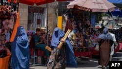 Burqa-clad Afghan women shop at a market area in Kabul on August 23, 2021, following the Taliban's military takeover of the country.