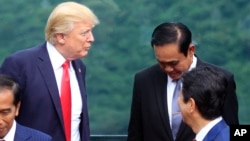 Presiden Donald Trump (kiri), berbicara dengan Perdana Menteri Thailand Prayuth Chan-ocha pada sesi foto pertemuan puncak Asia-Pacific Economic Cooperation (APEC) di Danang, Vietnam, 11 November 2017. 