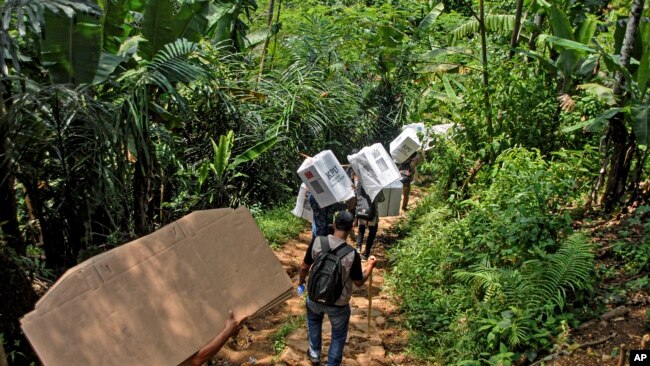 People carry ballot boxes to be distributed to polling stations ahead of the Feb. 14 election, in Kanekes village, Indonesia, Feb. 13, 2024.