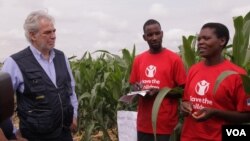 Beatrice Wisiki (R), a beneficiary of an EU-funded irrigation scheme in Zomba district, southern Malawi, tells EU commissioner Christos Stylianides about how she is benefiting from the project. (L. Masina/VOA)