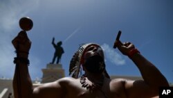 Gypsy Córdova exhala humo y sacude una maraca frente a un monumento a Juan Ponce de León, en una protesta para que se retiren los monumentos a colonizadores españoles en Puerto Rico.