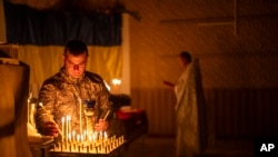 FILE— An Ukrainian serviceman of the 72nd Separate Mechanized Brigade, lights candles during a Christian Orthodox Easter religious service, in Donetsk region, Ukraine, May 4, 2024.