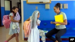 Attendance Clerk Katrice Grant speaks to siblings Melanie Pacheco, 8, left, and Marilynn Pacheco, 5, in the hallway before heading to their classrooms, at Algodones Elementary School in Algodones, New Mexico, Oct. 1, 2024.