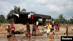 Quelques personnes au bord du fleuve Nun, Bayelsa, Nigeria, 27 novembre 2012.