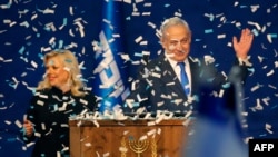 Israeli Prime Minister Benjamin Netanyahu and his wife, Sara, address supporters as confetti falls upon them at the Likud party campaign headquarters in the coastal city of Tel Aviv, after polls officially closed. 