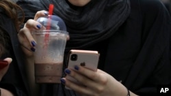In this Tuesday, July 2, 2019 photo, an Iranian woman works on her cell phone. Before Iranians can check out the latest offerings on Twitter or YouTube, they must search for the best workaround to bypass official censors. 
