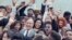 FILE - U.S. President George H.W. Bush is surrounded by cheering students from the Independent Living Program in Los Angeles, as Bush prepared to leave Los Angeles International Airport after presenting a Point of Light award in the area, May 21, 1990. Bush's "thousand points of light" concept is still going strong decades later. 