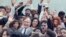 FILE - U.S. President George H.W. Bush is surrounded by cheering students from the Independent Living Program in Los Angeles, as Bush prepared to leave Los Angeles International Airport after presenting a Point of Light award in the area, May 21, 1990. 
