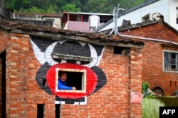 Hakka graffiti painter Wu Tsun-hsien poses in an empty old house near his home in the Taiwanese village of Ruan Chiao, March 30, 2019.