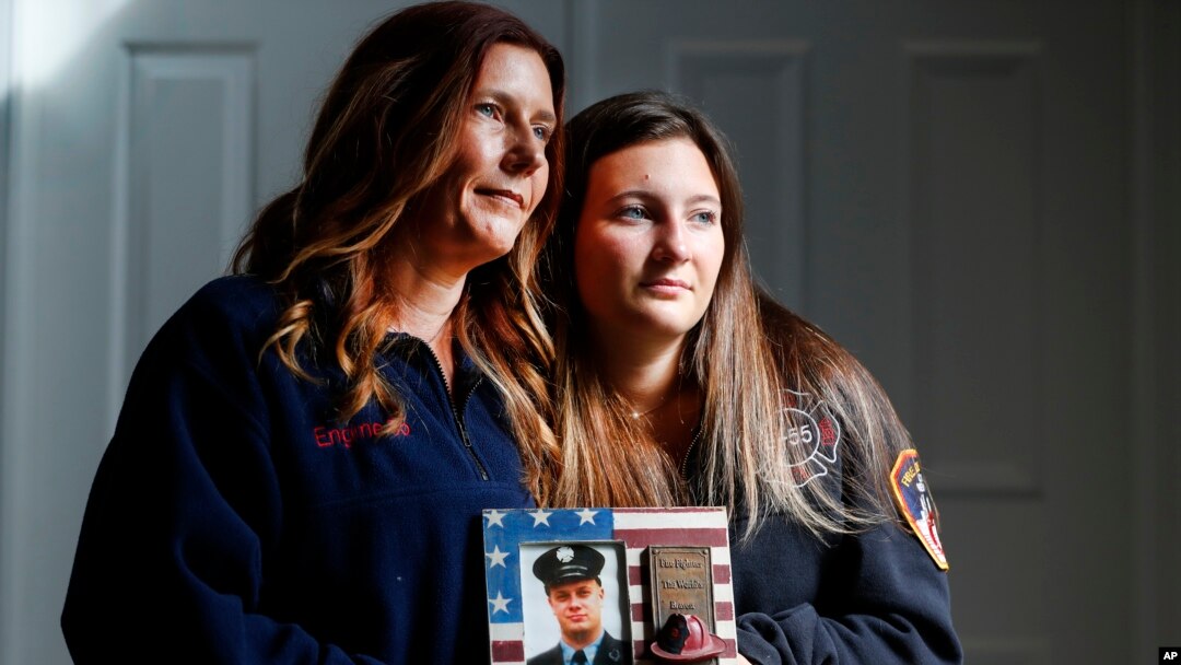 Pamela Jaroš i njena ćerka Kaprin sa fotografijom vatrogasca Kristofera Majkla Mozila koji je poginuo 11. septembra 2001. u Njujorku (Foto: AP/Noah K. Murray)