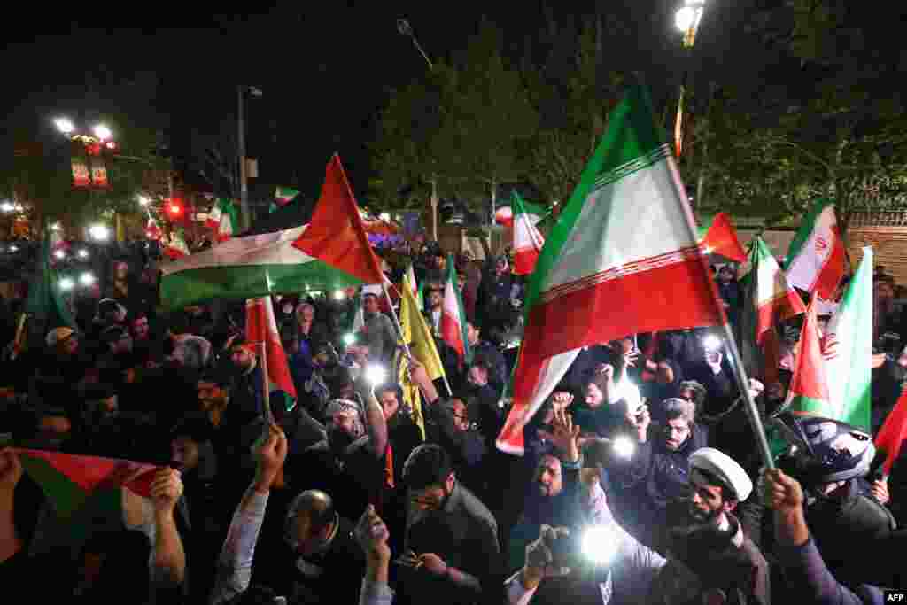 Demonstrators wave Iran&#39;s flag and Palestinian flags as they gather in front of the British Embassy in Tehran, April 14, 2024, after Iran launched a drone and missile attack on Israel.