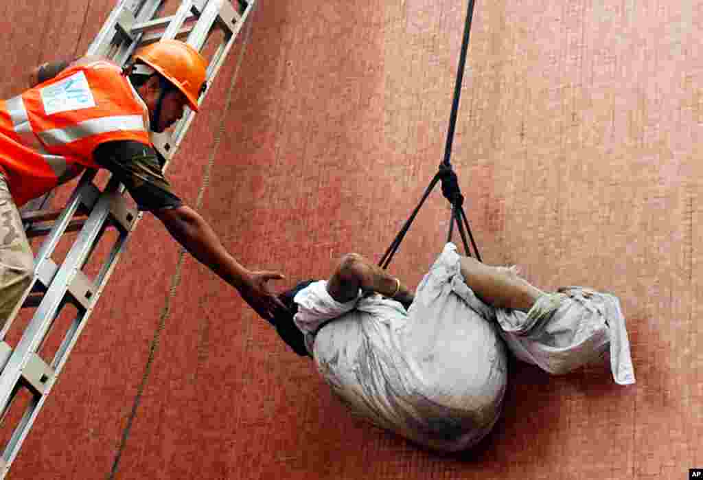 Rescue workers use ropes to evacuate a person from the hospital. The death toll from the fire has risen to 89. (AP Photo)