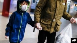 A child wears a protective mask and gloves in the subway system due to COVID-19 concerns, March 19, 2020, in New York.