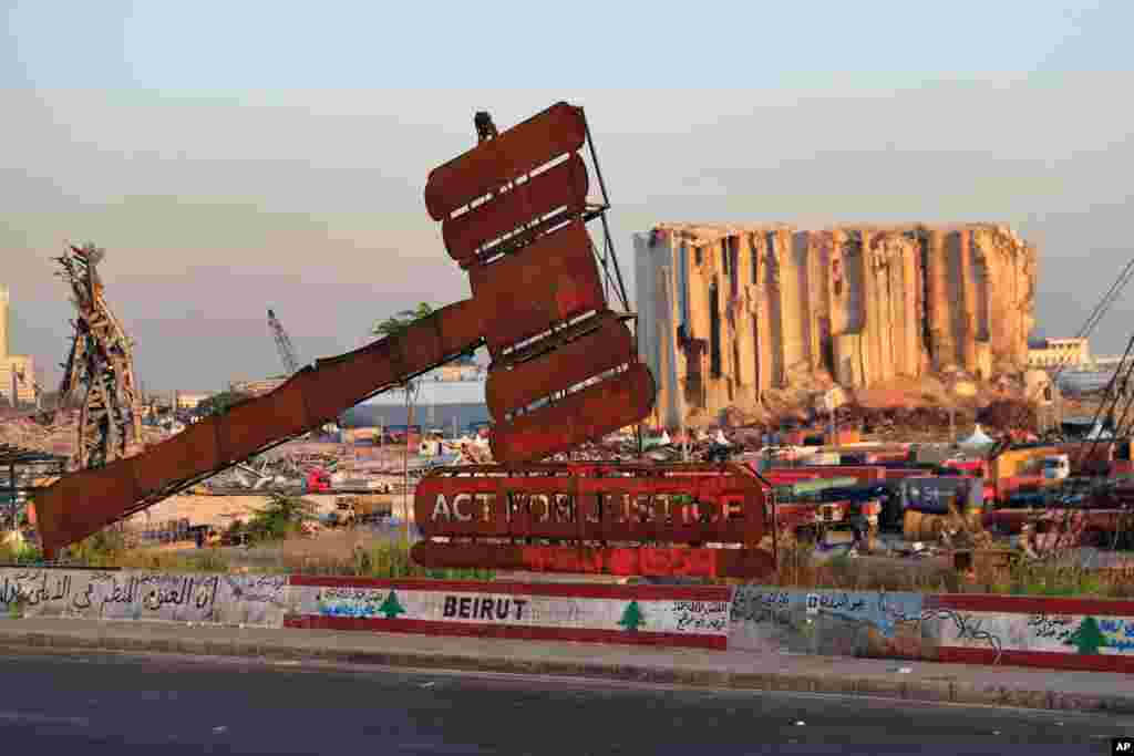 A justice symbol monument is seen in front of towering grain silos that were gutted in the massive August 2020 explosion at the port that claimed the lives of more than 200 people, in Beirut, Lebanon.