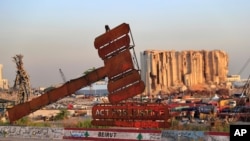 A justice symbol monument is seen in front of towering grain silos that were gutted in the massive August 2020 explosion at the port that claimed the lives of more than 200 people, in Beirut, Lebanon.
