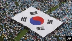 FILE - Orang-orang membawa bendera nasional Korea Selatan saat unjuk rasa anti-Korea Utara di Seoul, 6 Juni 2011. Pusat Penanggulangan Terorisme Nasional Korea Selatan menaikkan tingkat pengawasan teror negara itu ke status 'waspada', 2 Mei 2024.