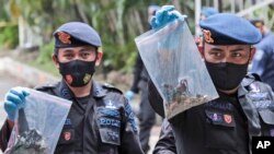 Anggota Jihandak, Senin (29/3), memperlihatkan kantong plastik berisi sejumlah barang bukti yang dikumpulkan di sekitar lokasi ledakan bom di Gereja Katedral Makassar, Sulawesi Selatan pada Minggu, 28 Maret 2021. (Foto: Yusuf Wahil/AP)