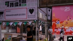 People walk by as vendors set up their stores at a popular shopping district in Shanghai on Oct. 12, 2024.