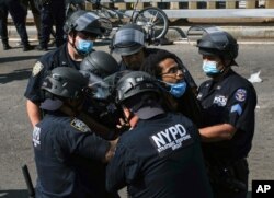 A Black Lives Matter protester is apprehended by NYPD officers on the Brooklyn Bridge, July 15, 2020, in New York.