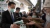 Thailand's Public Health Minister Anutin Charnvirakul, left, distributes masks to commuters during a campaign for wearing masks and washing hands at the skytrain station in Bangkok, Feb. 7, 2020. 