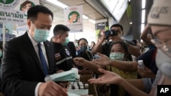 Thailand's Public Health Minister Anutin Charnvirakul, left, distributes masks to commuters during a campaign for wearing masks and washing hands at the skytrain station in Bangkok, Feb. 7, 2020. 