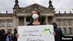 A person holds a placard reading "Solidarity with women in Afghanistan" during a protest against support for the Taliban, in front of the lower house of parliament, the Bundestag, in Berlin, Germany, Aug. 17, 2021.